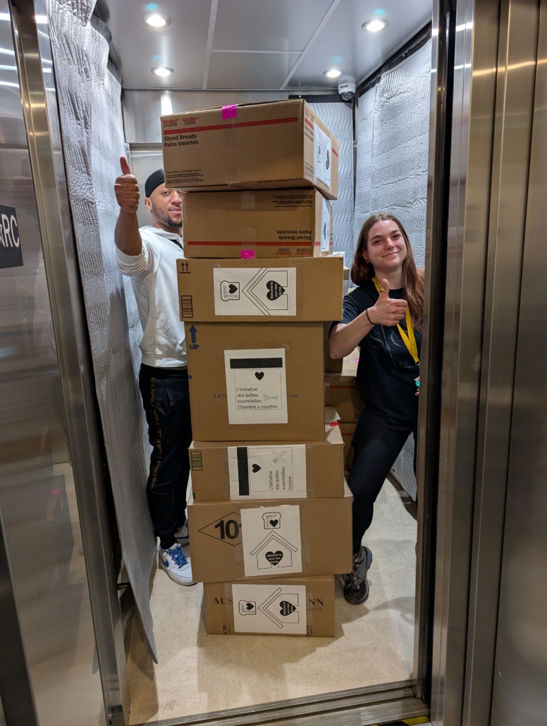 Deux membres de l'équipe du Sac à dos utilise l'ascenseur pour porter des cartons